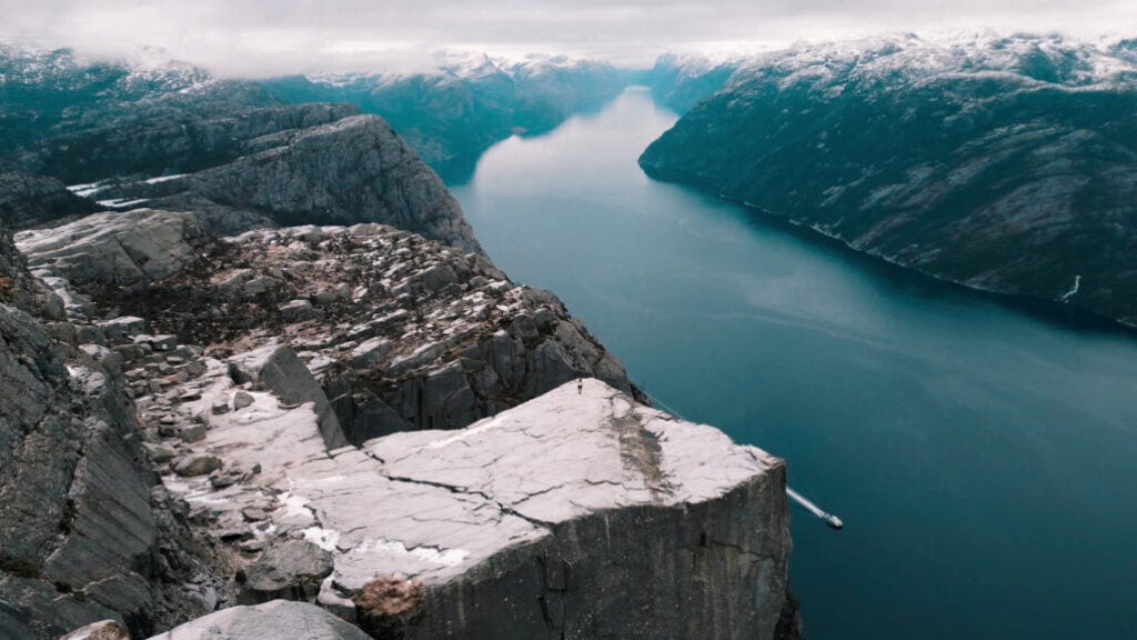 Preikestolen i vinterlandskap med snødekte fjell og Lysefjorden under