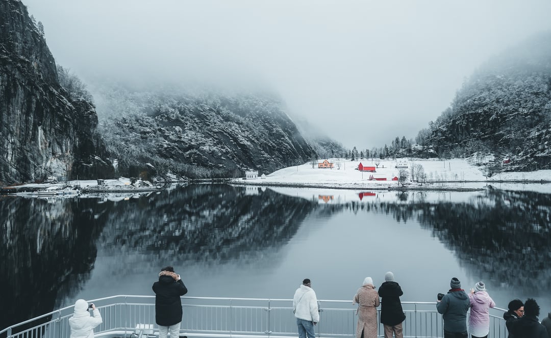 Guests on a fjord cruise enjoying the view of a mysterious winter landscape at Mostraumen near Bergen