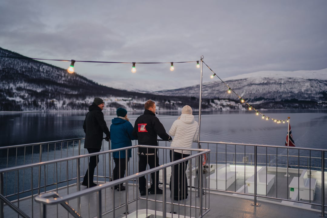 tree gjester og en guide speider etter hval i fjordene utenfor Tromsø.
