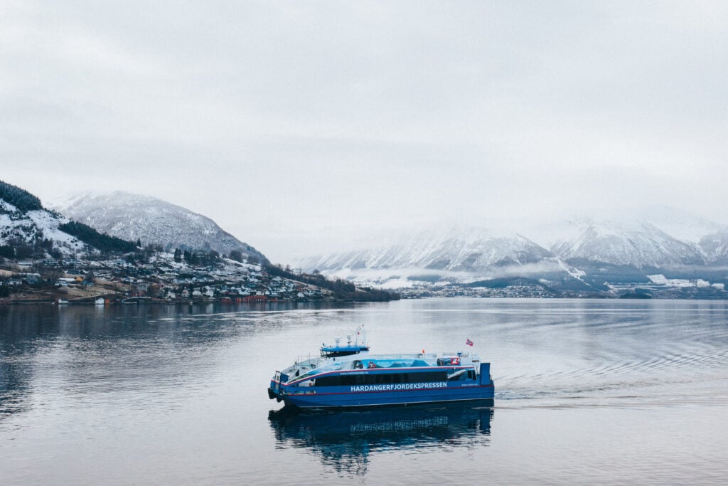 Hardangerfjord Express boat sailing through snow-covered Hardangerfjord near Rosendal, Norway