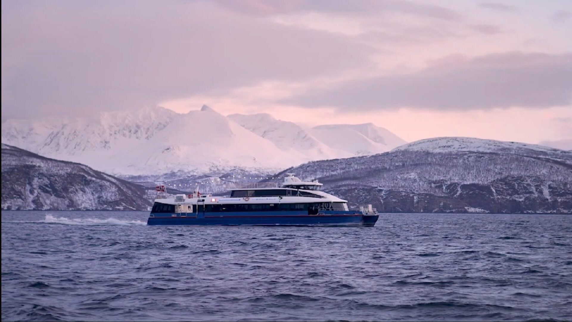 Rygerdronningen catamaran sailing towards Skjervøy with snowy mountains in Tromsø fjord during whale watching cruise