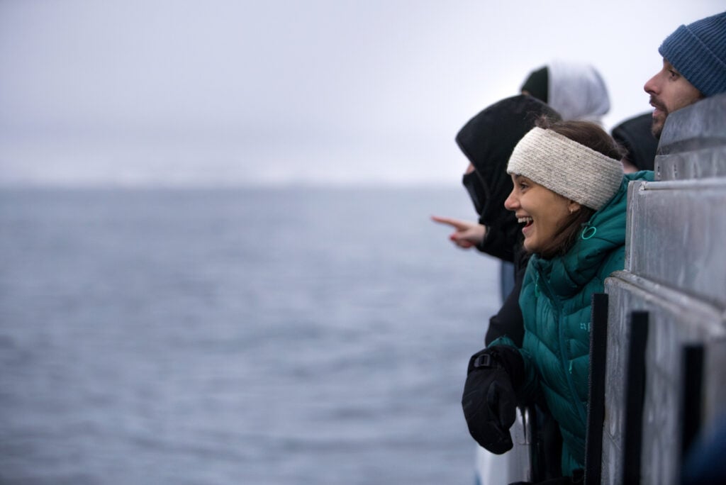 Close-up of happy guests on the outside deck of Rygerdronningen during whale watching tour in Tromsø Arctic fjords