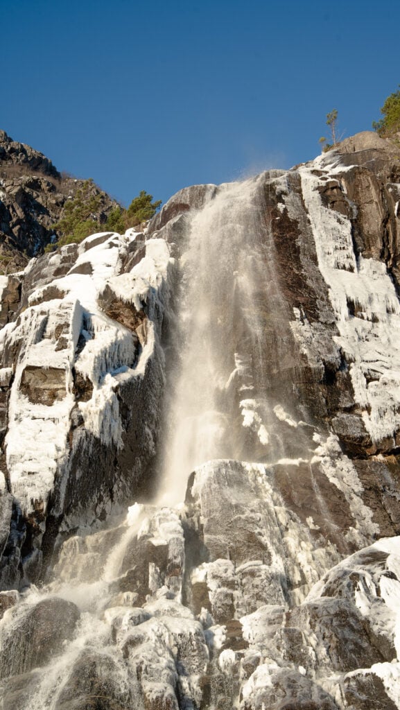 Partially frozen Hengjane waterfall cascading down steep rock walls along the Lysefjord in winter