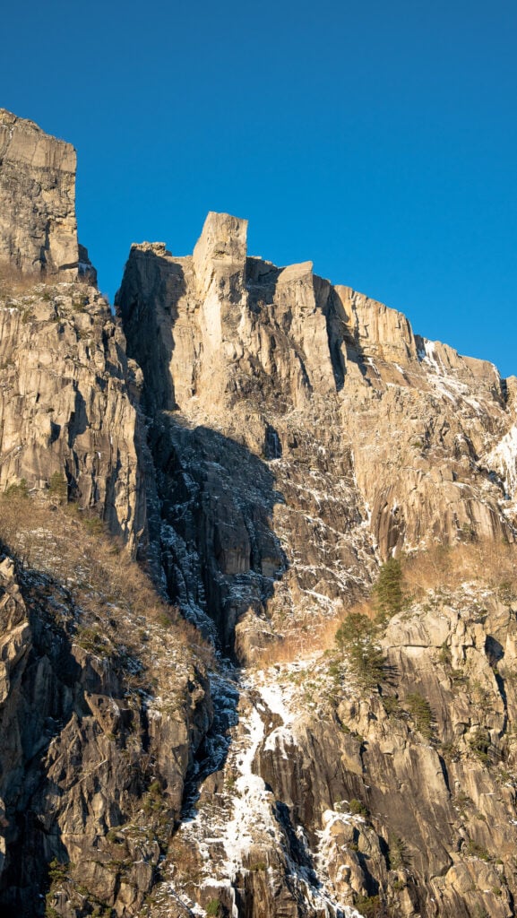 Preikestolen (Pulpit Rock) rising above the Lysefjord during winter, photographed from a fjord cruise below