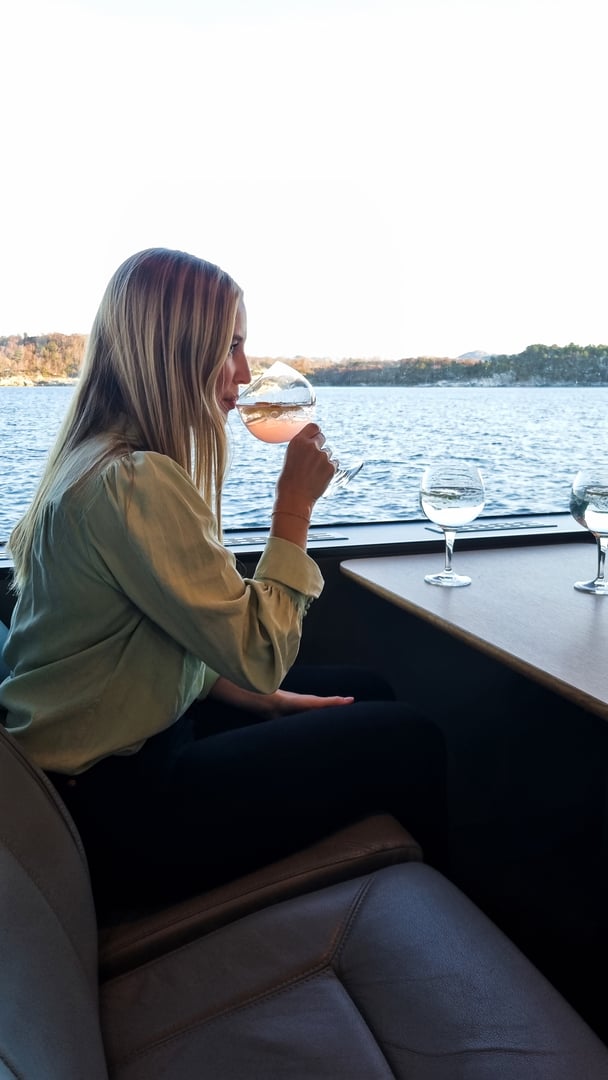 Ginsmaking på fjorden. Dame som nyter et glass pink gin.