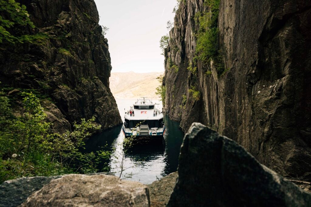 Rødne fjord cruise boat navigating in the narrow Fantahålå between steep rock walls in the Lysefjord
