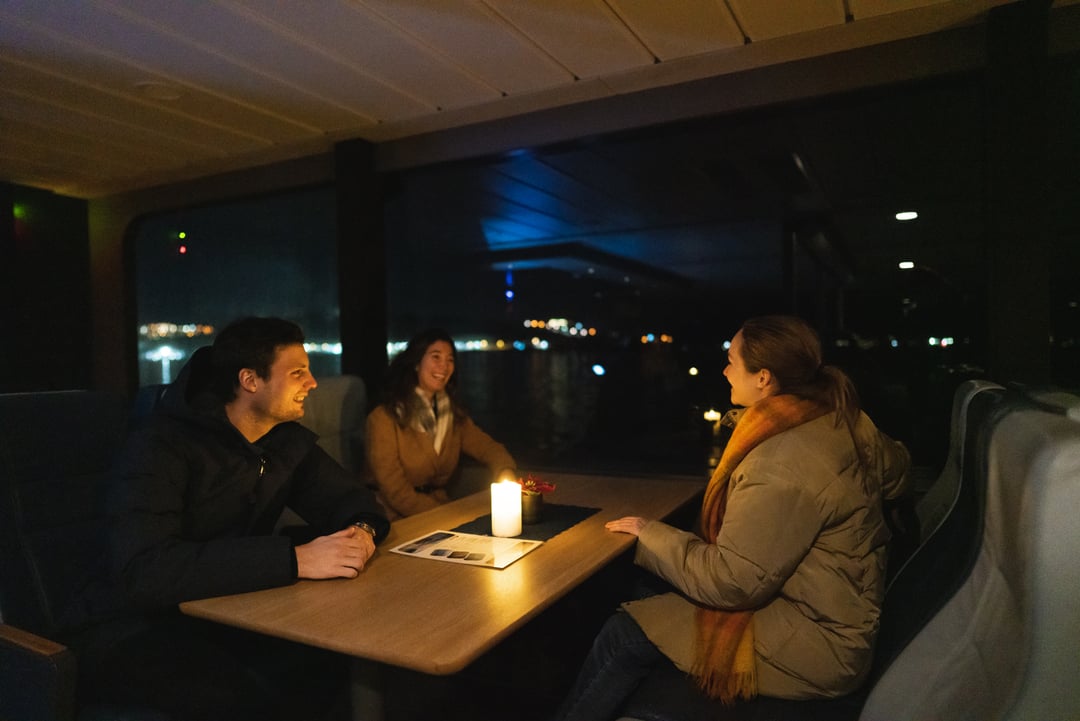 a gropu of friends enjoying the big panoramic windows while taking a boat tour to enjoy the Northern lights in Tromsø
