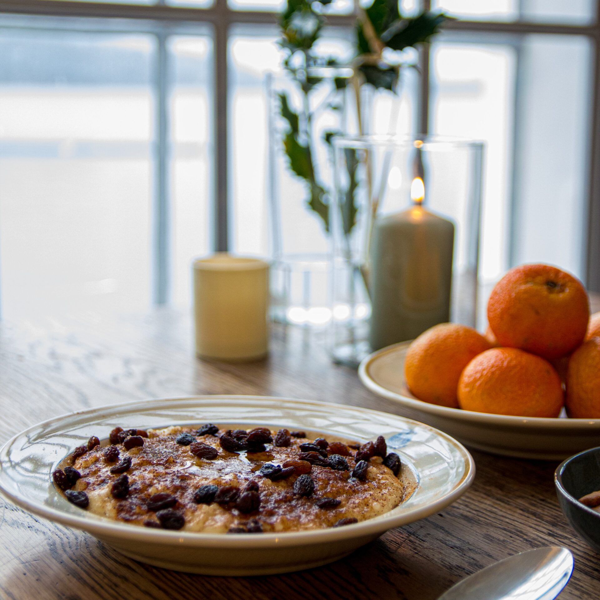 Nærbilde av en tallerken med rykende varm julegrøt og tente lys på bordet under arrangementet Jul på fabrikken i Salhus.