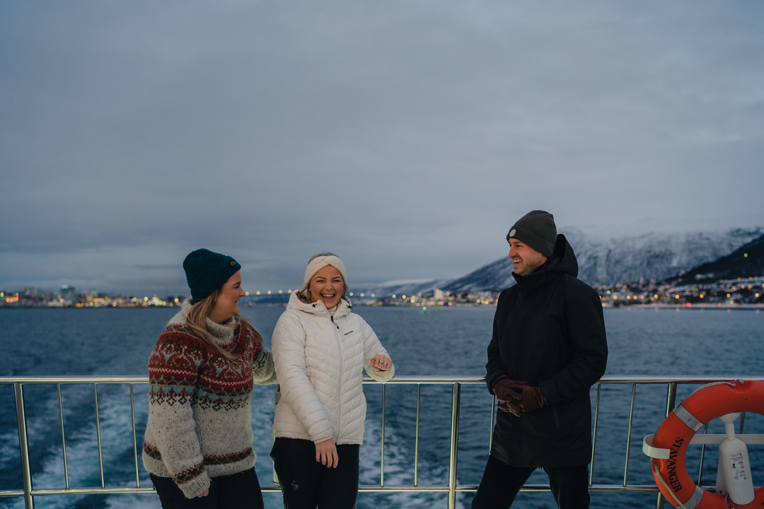 Group of guests on the outdoor deck enjoying the blue polar night light and arctic scenery during a whale watching tour in Tromsø, Norway
