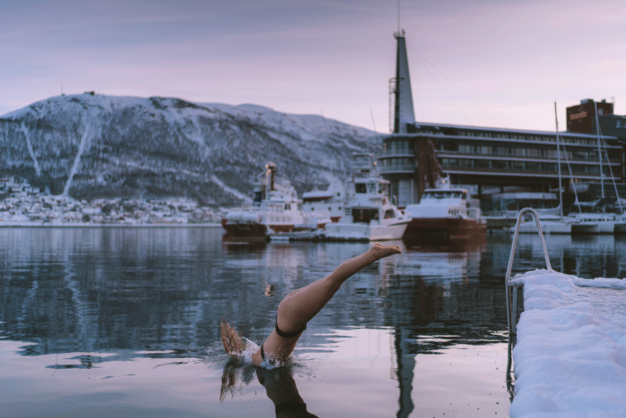 Woman jumping into the cold water of Tromsøsundet after a sauna session.