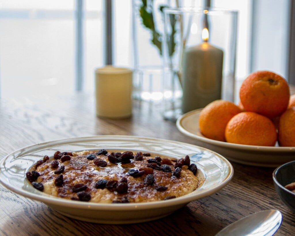 Nærbilde av en tallerken med rykende varm julegrøt og tente lys på bordet under arrangementet Jul på fabrikken i Salhus.