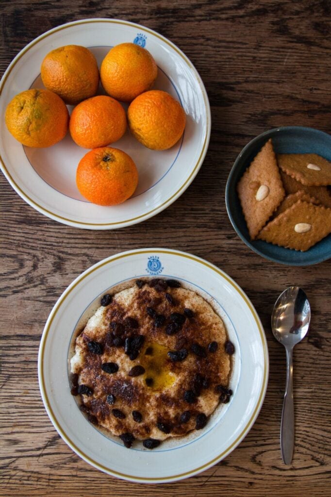 Flat lay-bilde av julegrøt med skje, pepperkaker og mandariner, servert under arrangementet Jul på fabrikken i Salhus.