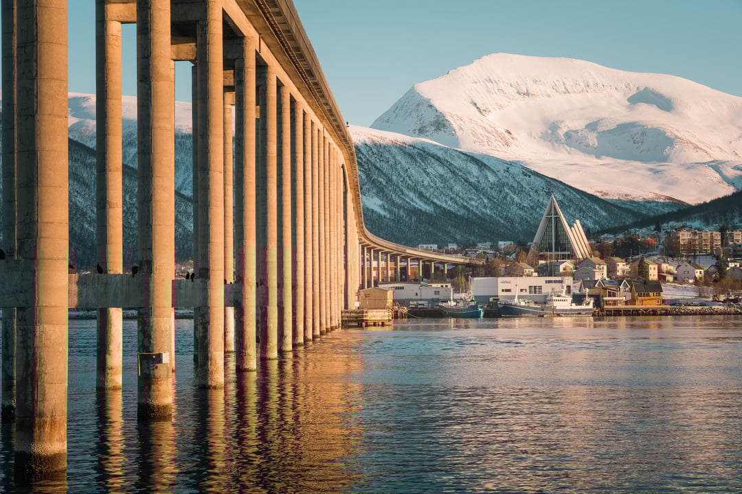 Arctic Cathedral and Tromsø Bridge in winter light, with snowy mountains in the background.