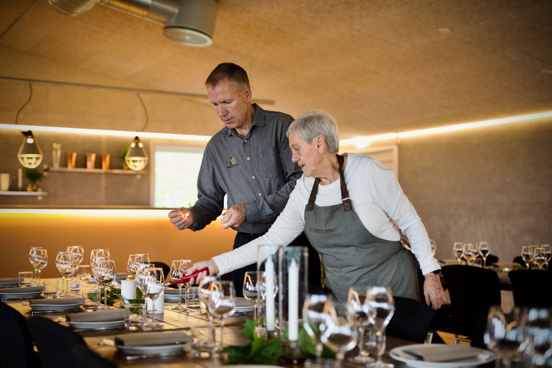 Forberedelser til vinsmaking på Hebnes Vingard, der Arild Hebnes og en ansatt dekker bordene i Vinstova før gjestene ankommer med fjordcruise.