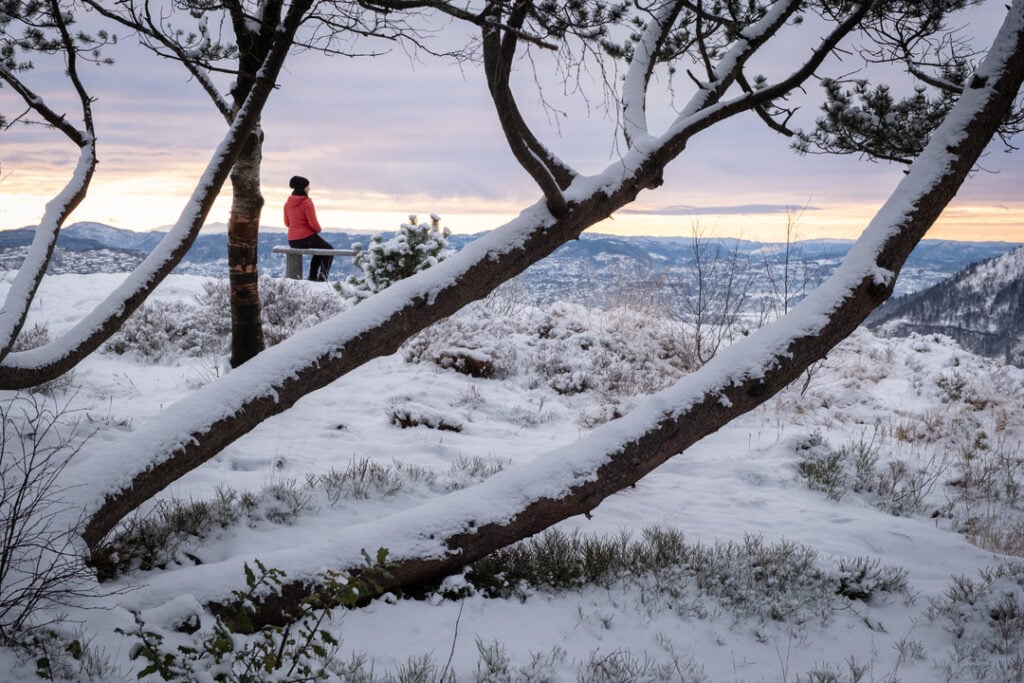 Person enjoying a winter hike with panoramic view over Bergen and surrounding mountains