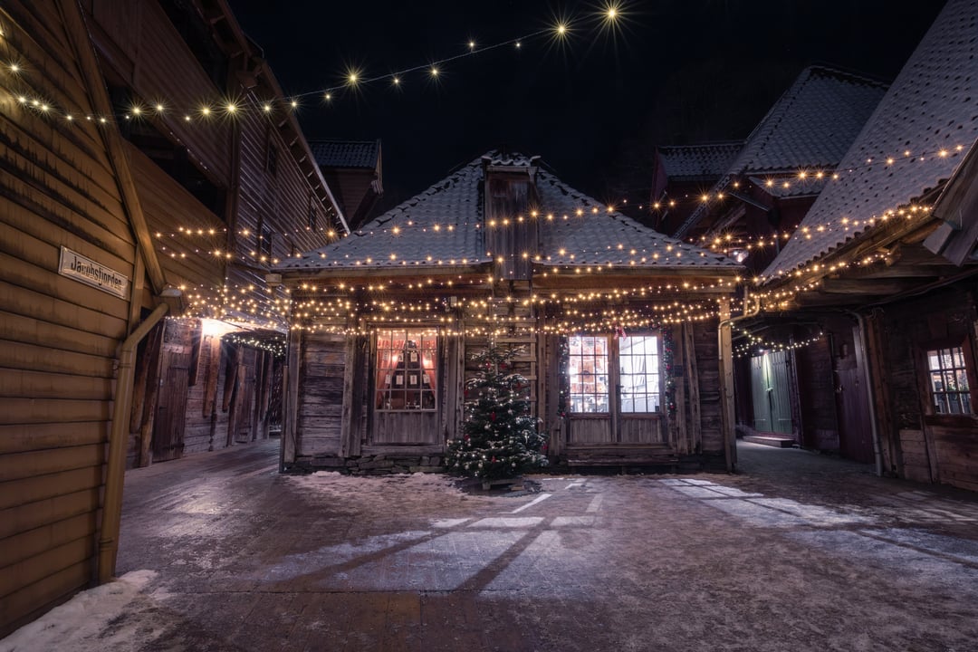 Traditional wooden houses at Bryggen in Bergen decorated with Christmas lights on a snowy winter evening