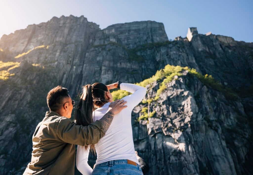 Par som ser opp mot fjellveggen under Preikestolen i Lysefjorden