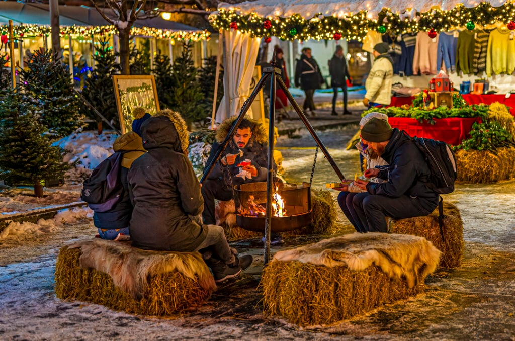 Visitors warming up by an open fire at the Bergen Christmas Market during winter