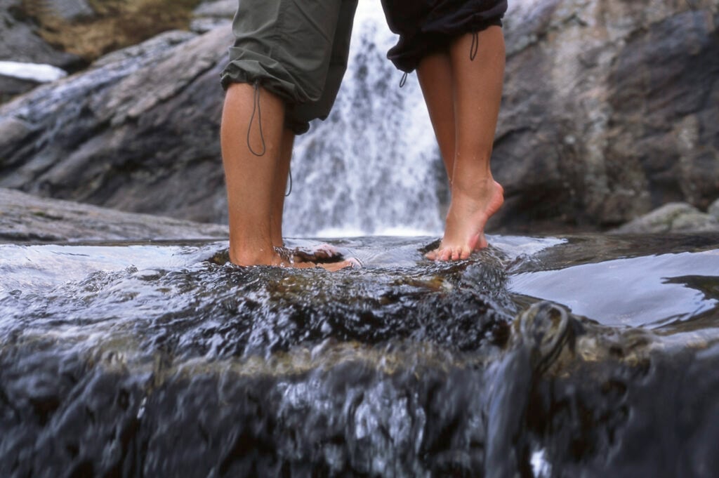 Nærbilde av par som går gjennom en fjellbekk på vei til Kjerag i Lysefjorden