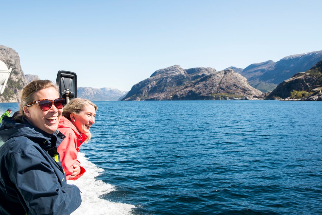 Zwei Frauen genießen die Fahrt mit dem Boot auf dem Lysefjord, umgeben von Bergen und offenem Fjordwasser