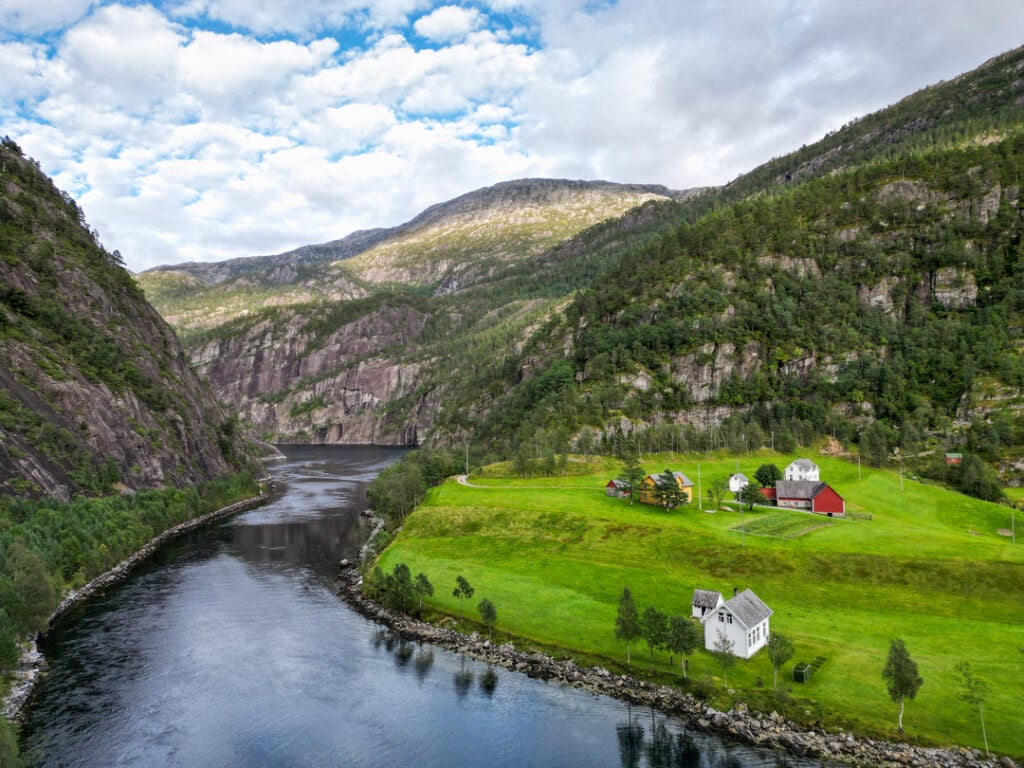 Gård ved fjord med fjell og elv i Mostraumen området nær Bergen