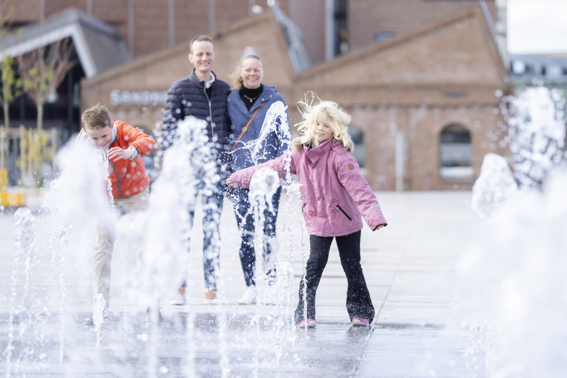 Family enjoying the fountains in Sandnes city centre near the harbour