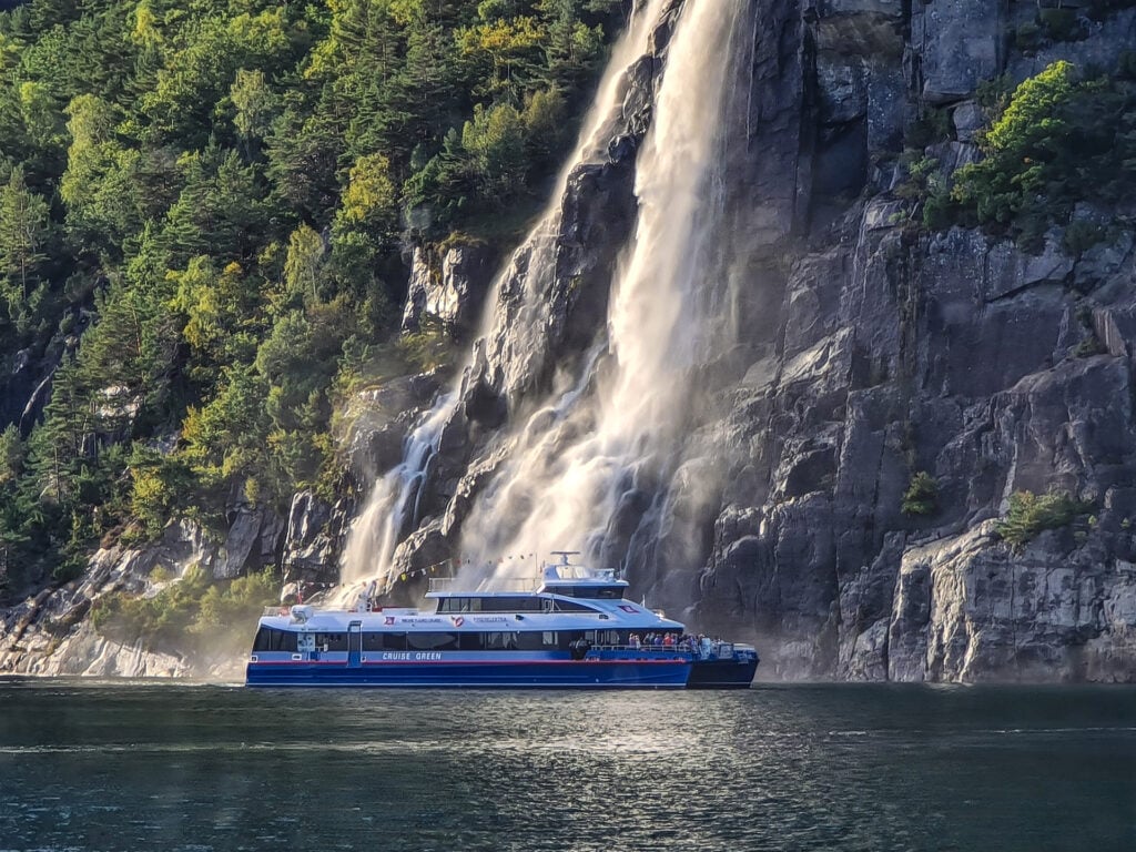 Das Elektroschiff MS Rygerelektra fährt nah am mächtigen Hengjanefossen vorbei auf der Lysefjord-Kreuzfahrt zum Preikestolen ab Stavanger