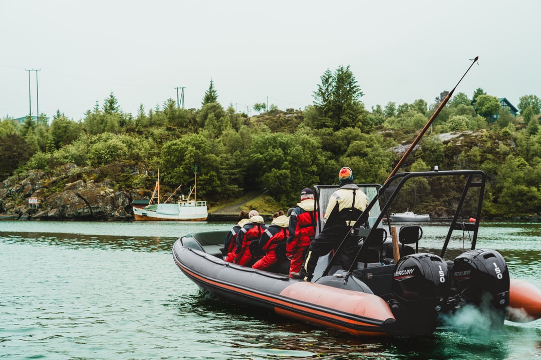 Rødne RIB with twin engines speeding past small islands and fishing boats west of Bergen