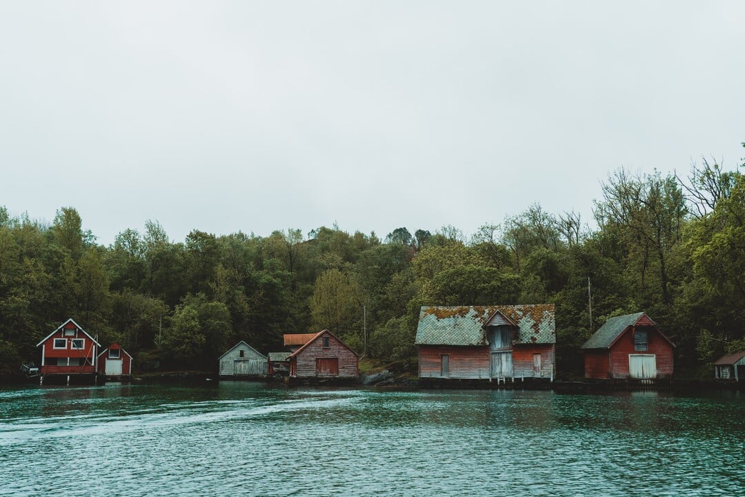 A row of old red boathouses along a wooden shoreline among the islands west of Bergen.