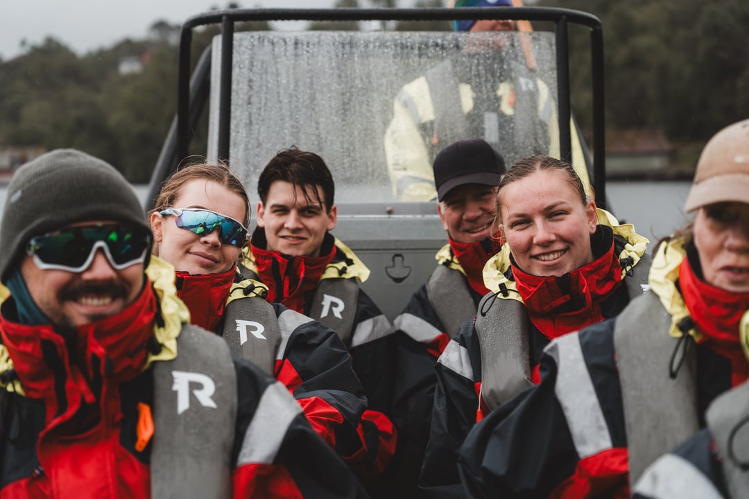 Close-up of smiling RIB guests in Rødne protective suits during a tour near Bergen